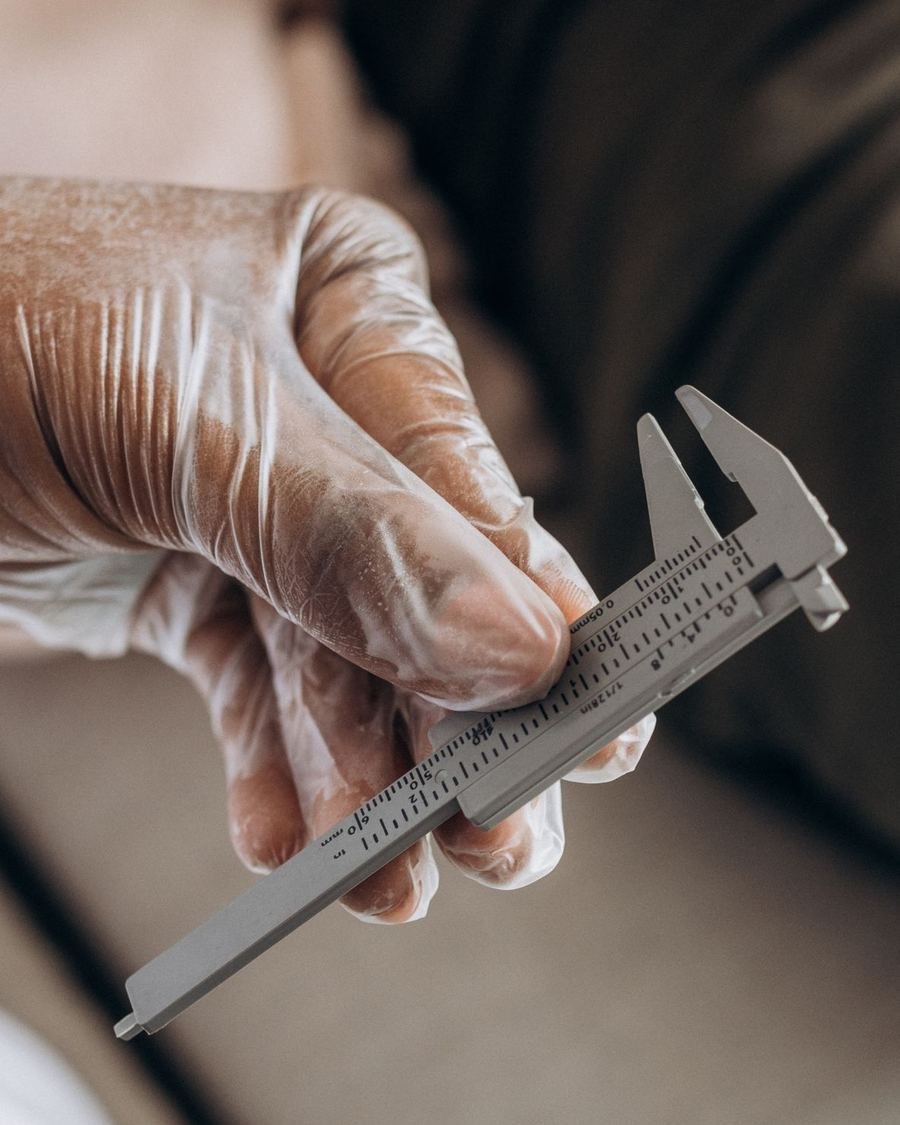 Gloved hand measuring an instrument with a precision caliper